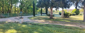 A gravel path leading through a well-maintained garden with trees and a lamp post.