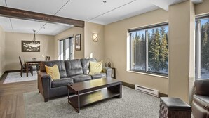 A modern living room with a sofa, coffee table, dining table, and chairs. - Slopeside Condo w/ Chairlift Views & Pool (Breckenridge)