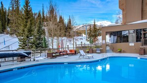 A swimming pool with lounge chairs and a view of a snowy mountain range. - Slopeside Condo w/ Chairlift Views & Pool (Breckenridge)