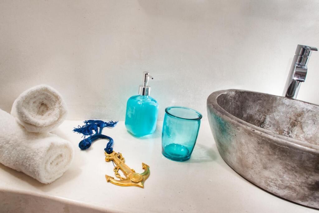 Un bagno con lavandino, asciugamano, dispenser di sapone e bicchiere.