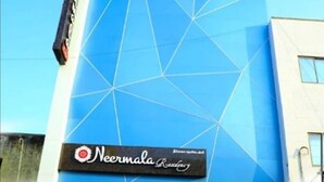 Ένα κτίριο με γεωμετρική πρόσοψη και μια επιγραφή που αναγράφει «Neemala Residency».