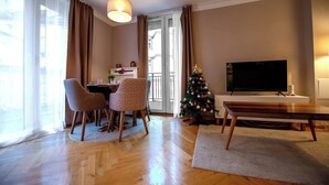 Ein Wohnzimmer mit Essbereich, Fernseher, Weihnachtsbaum und Balkon.