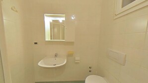 Ein kleines Badezimmer mit Waschbecken, Toilette und Spiegel.