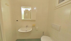 Ein kleines Badezimmer mit Waschbecken, Toilette und Spiegel.