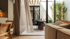 En modern inredning med ett matbord och stolar i trä, en soffa och utsikt över en balkong med grönska.