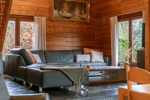 Ein gemütliches Cabin-Interieur mit einer Eckcouch, einem Fernseher und einem Gemälde einer Waldszene.