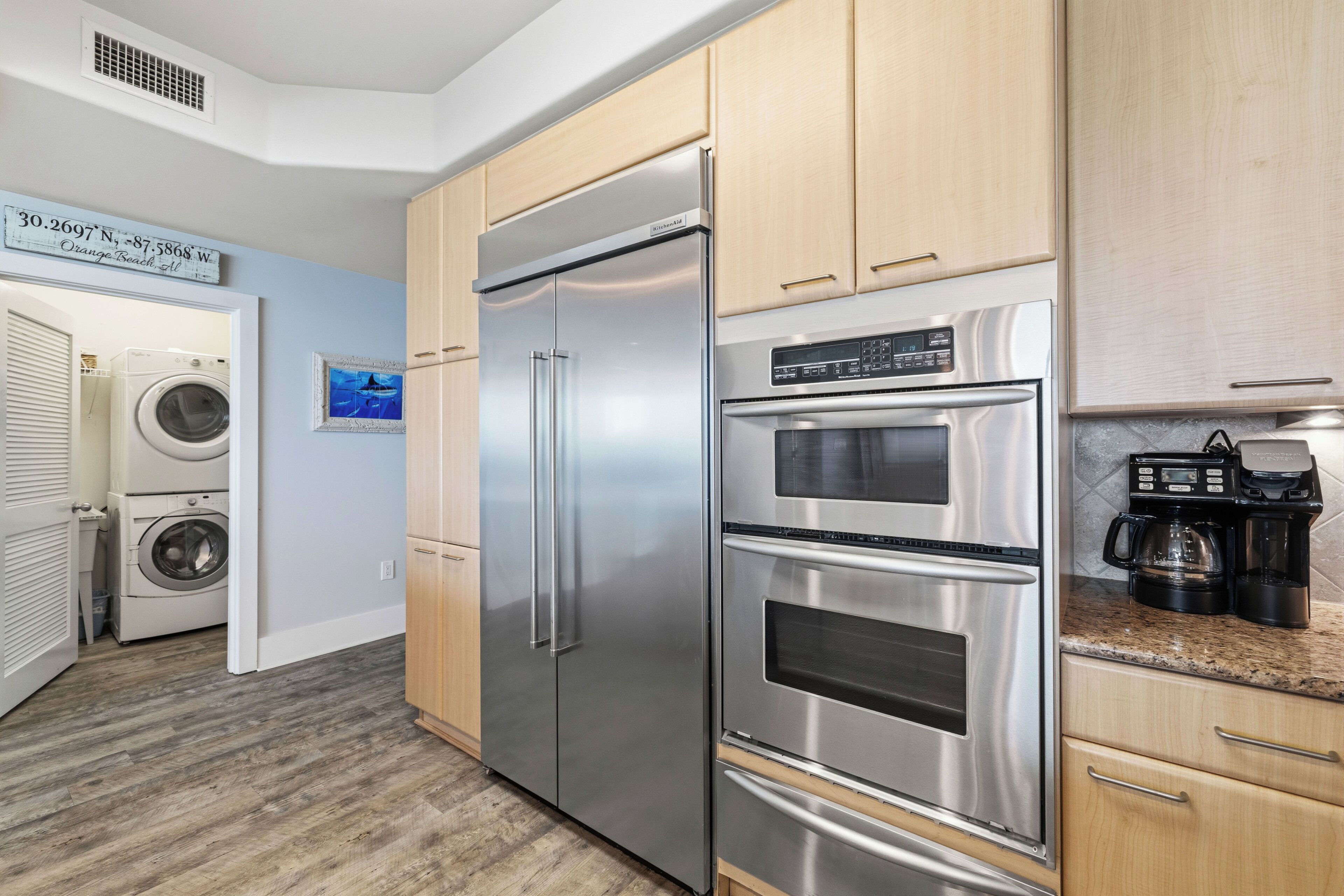 A modern kitchen with stainless steel appliances, wooden cabinets, and a built-in washer and dryer.