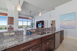 A modern kitchen with granite countertops, stainless steel appliances, and pendant lighting.