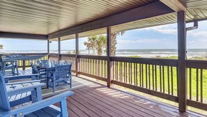 Un'area esterna coperta con panche e tavoli in legno, con vista sull'oceano.