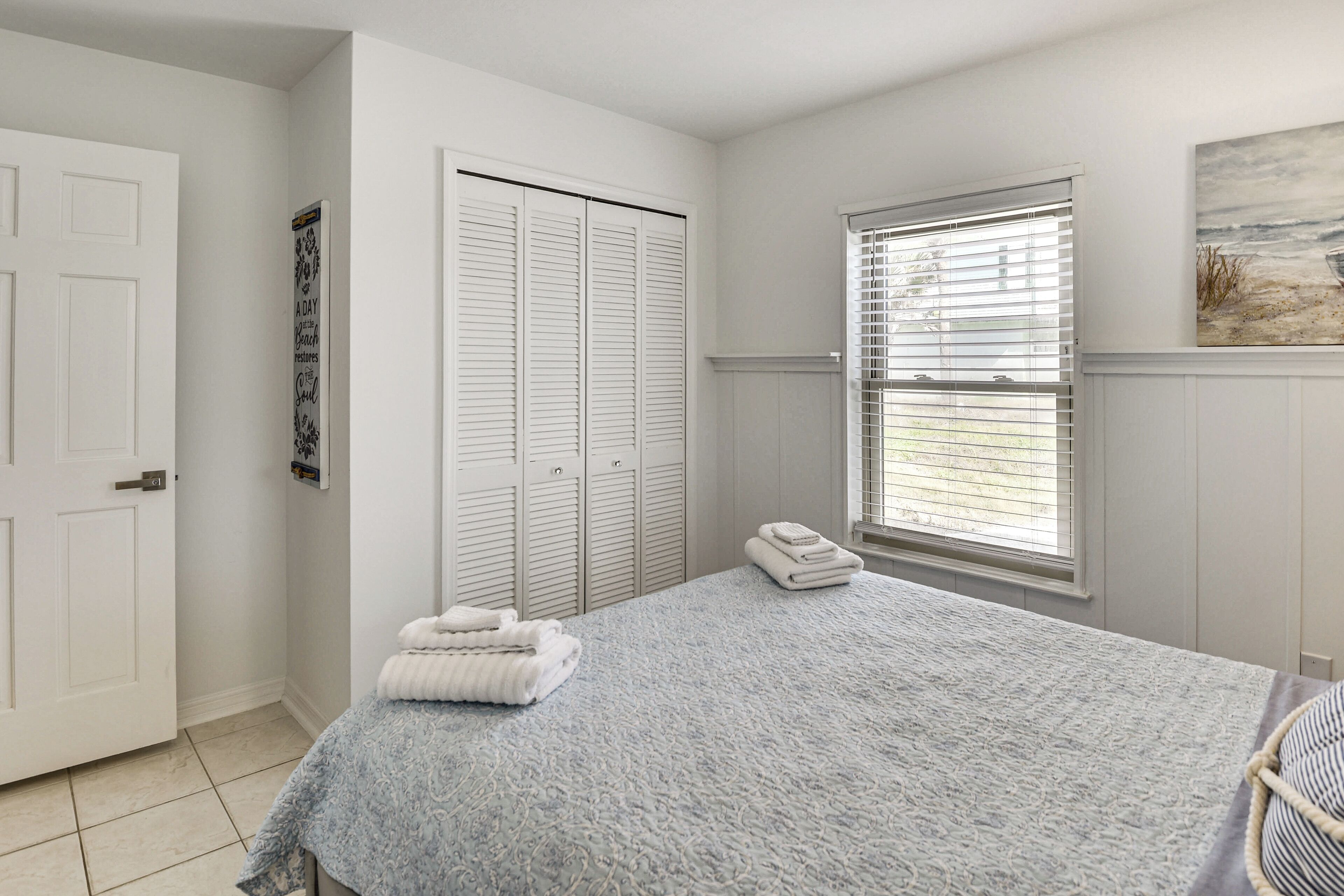 Un dormitorio con cama, ventana con persianas, puerta y armario.