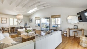 Un'ampia zona giorno con un grande divano bianco, un tavolino in legno e una ventola a soffitto.