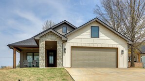 A modern house with a stone facade, a garage, and a covered patio area. - Steps From the Water! Grand Lake Getaway w/ Patio (Afton)