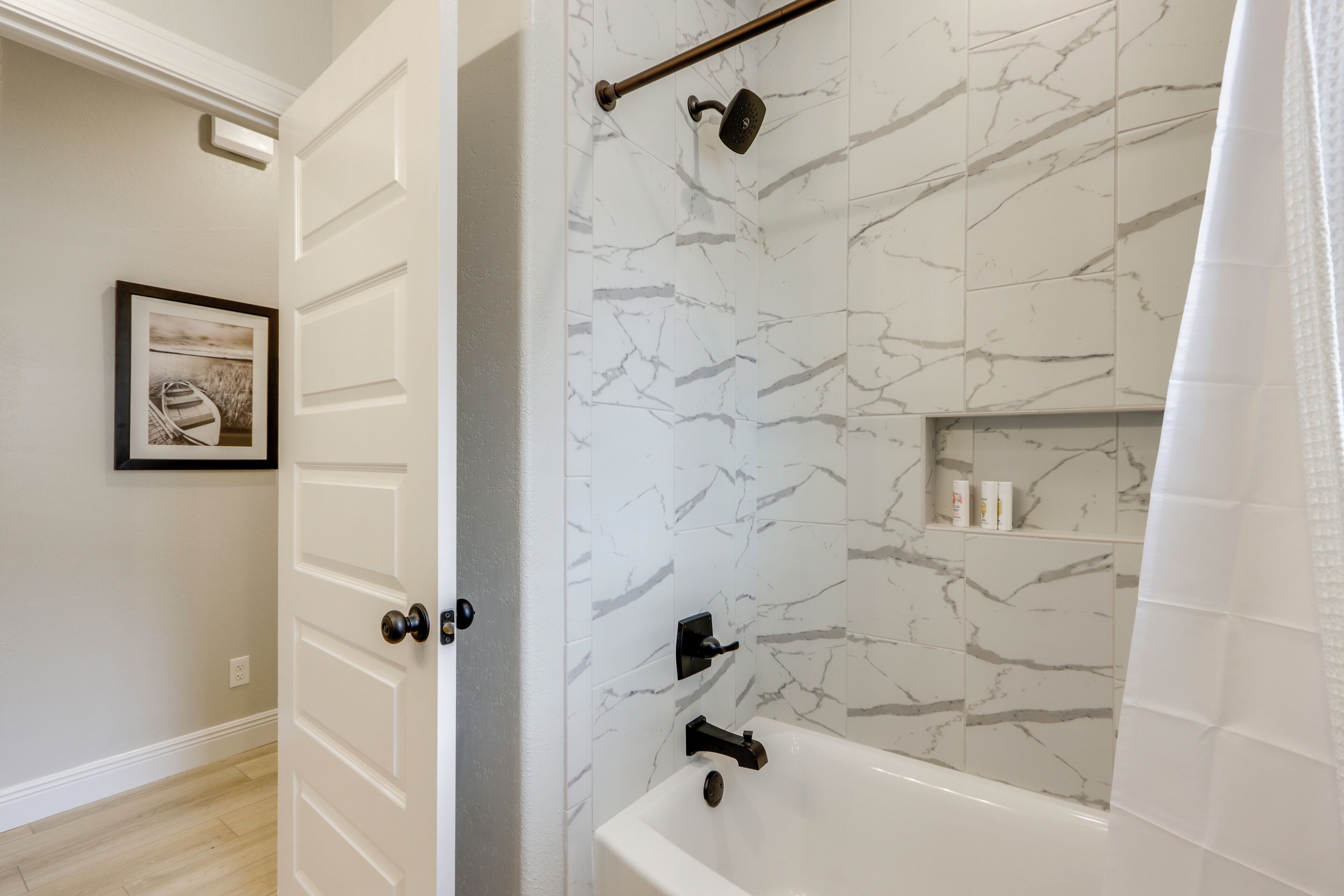 A bathroom with a bathtub, marble walls, and a shower curtain.
