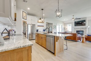 Una cocina moderna con una isla central, armarios de madera y electrodomésticos de acero inoxidable, además de una chimenea.