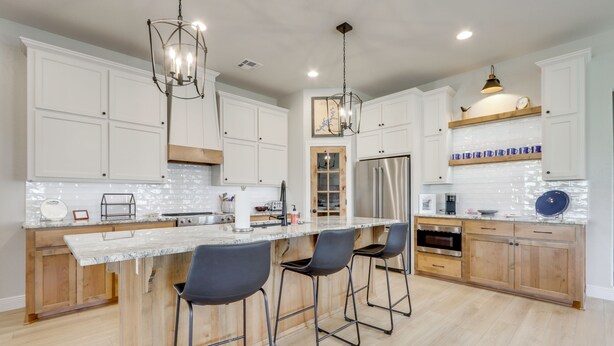 A modern kitchen with white cabinets, a marble island, bar stools, stainless steel appliances, and pendant lighting. - Steps From the Water! Grand Lake Getaway w/ Patio (Afton)