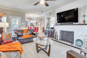 A living room with a fireplace, a television, and a dining area with red chairs.