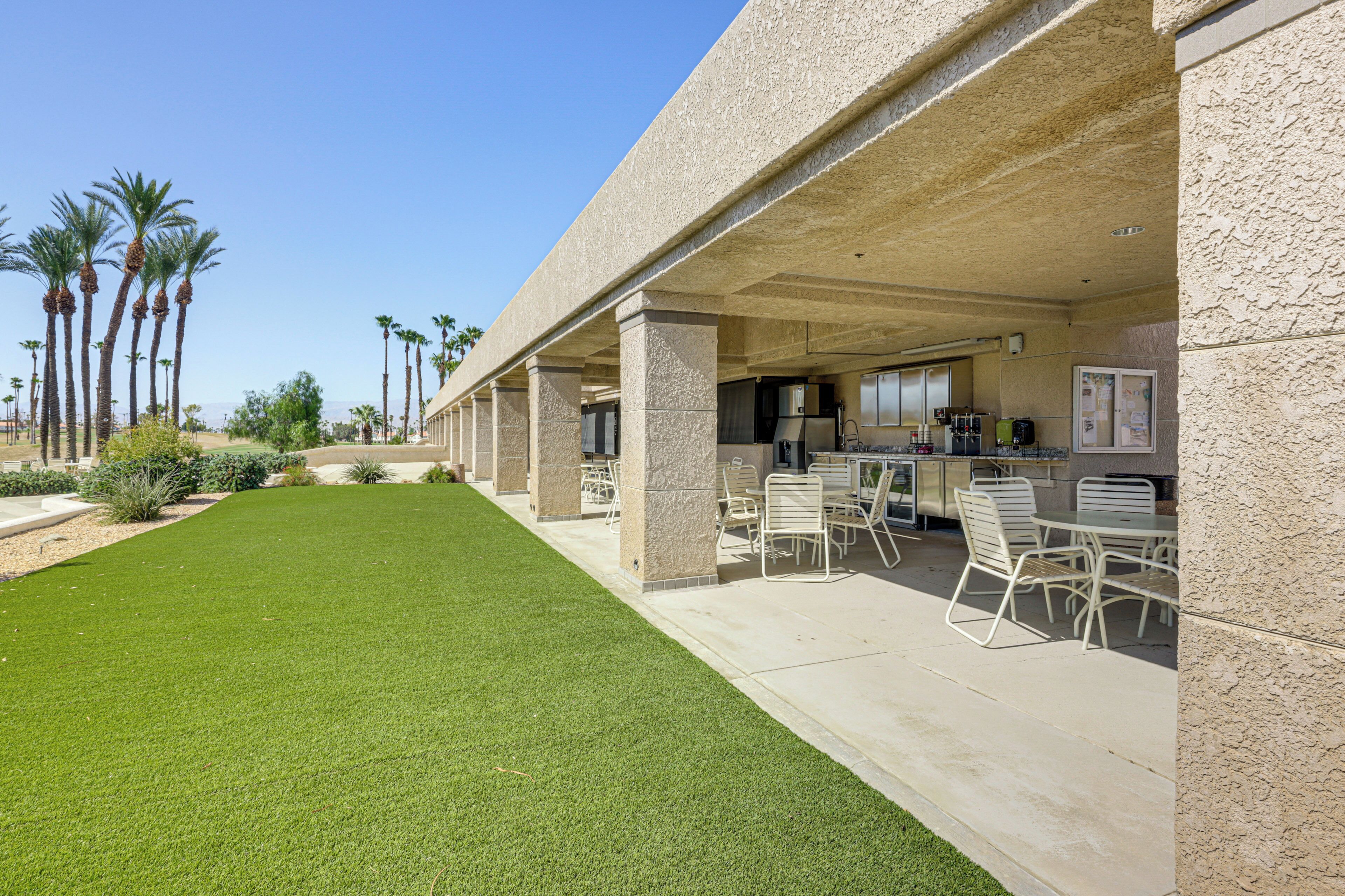 Un espacio al aire libre techado con patio, asientos y una zona de cocina.