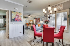 A dining area with a glass table, red chairs, and a chandelier.