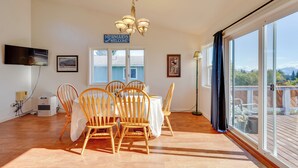 A dining area with a table and chairs, a chandelier, and a sign that reads "Mermaids Welcome". - < 1 Mi to Pioneer Ave: Homer Base w/ Fire Pit! (Homer)