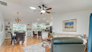 A spacious living room with a sofa, dining area, and kitchen in the background. - Golf + Poolside Bliss! Retreat 2 Mi to Lake Sumter (The Villages)
