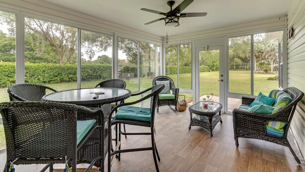 A covered patio with wicker furniture, a ceiling fan, and large windows offering a view of the outdoors. - Golf + Poolside Bliss! Retreat 2 Mi to Lake Sumter (The Villages)