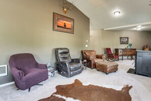 A living room with a leather armchair, a recliner, a brown leather ottoman, a cowhide rug, a fireplace, and a framed picture on the wall.