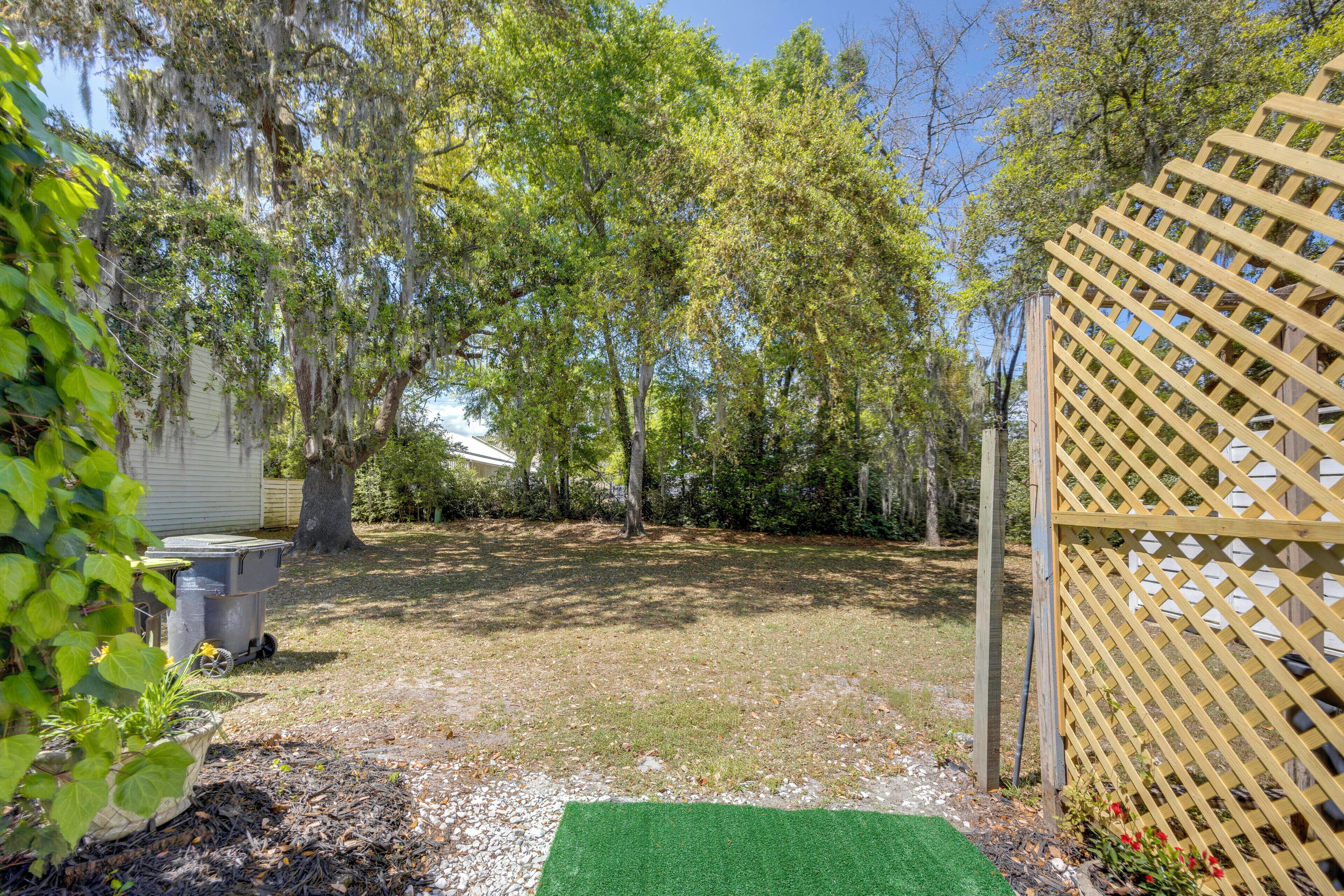 Un patio trasero con cerca de madera, área de césped artificial verde y árboles.
