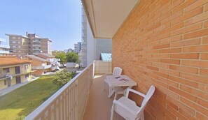 Ein Balkon mit Tisch und Stühlen, eine Ziegelwand und Blick auf umliegende Gebäude.
