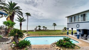 Piscina con palme, vista sull'oceano e un edificio dal design moderno.