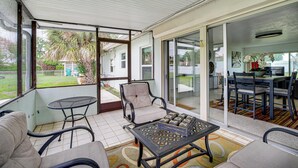 En overdækket terrasse med et spisebord, stole og en komfortabel stol.