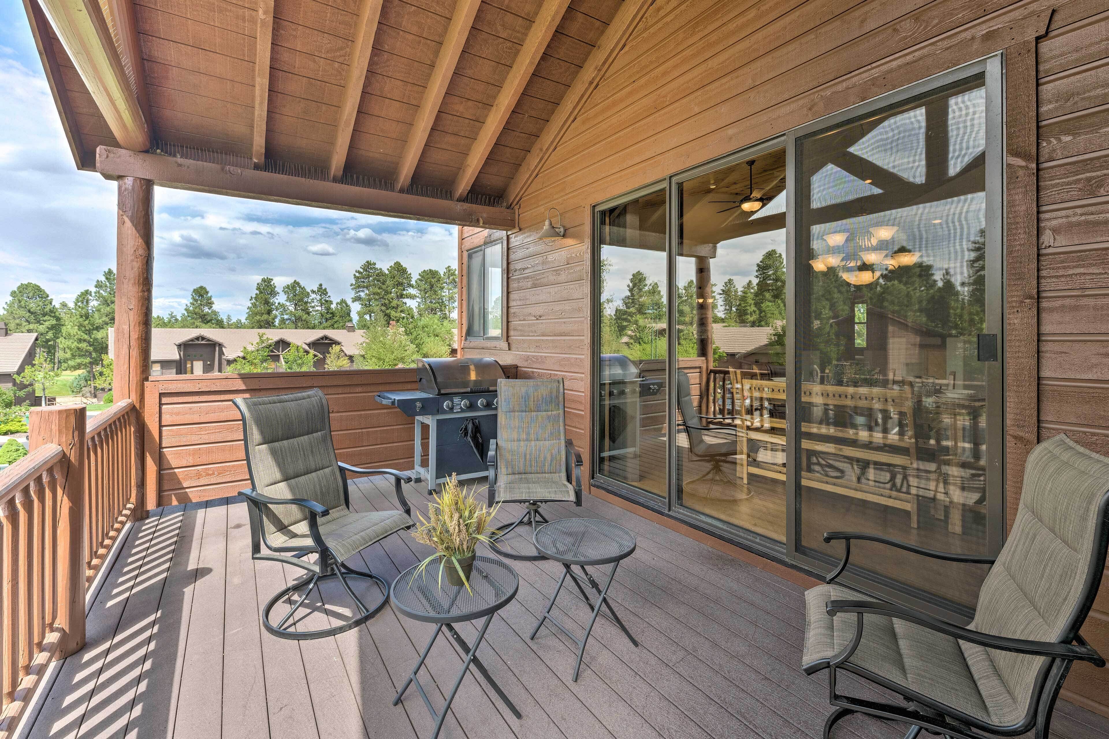 A wooden deck with a grill, chairs, and a table.