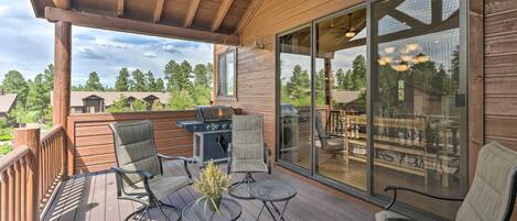 A wooden deck with a grill, chairs, and a table.