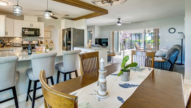 A modern kitchen with a dining area, wooden ceiling beams, and a large window. - Private Yard + Heated Pool: Port Charlotte Oasis (Port Charlotte)