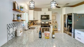 A modern kitchen with white cabinets, a granite countertop, and stainless steel appliances. - Private Yard + Heated Pool: Port Charlotte Oasis (Port Charlotte)