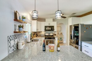 A modern kitchen with white cabinets, a granite countertop, and stainless steel appliances. - Private Yard + Heated Pool: Port Charlotte Oasis (Port Charlotte)