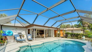 A pool area with a glass enclosure, lounge chairs, and a dining area. - Private Yard + Heated Pool: Port Charlotte Oasis (Port Charlotte)