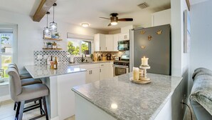 A modern kitchen with a central island, white cabinetry, and a ceiling fan. - Private Yard + Heated Pool: Port Charlotte Oasis (Port Charlotte)