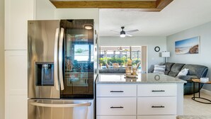 A modern kitchen with a built-in refrigerator, a dining area with a view, and a living room with a sofa and a lamp. - Private Yard + Heated Pool: Port Charlotte Oasis (Port Charlotte)