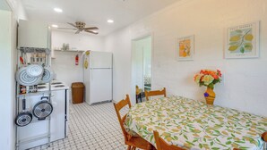 Une cuisine de taille réduite, dotée d’un ventilateur de plafond, d’un réfrigérateur et d’un coin repas avec une table et des chaises.