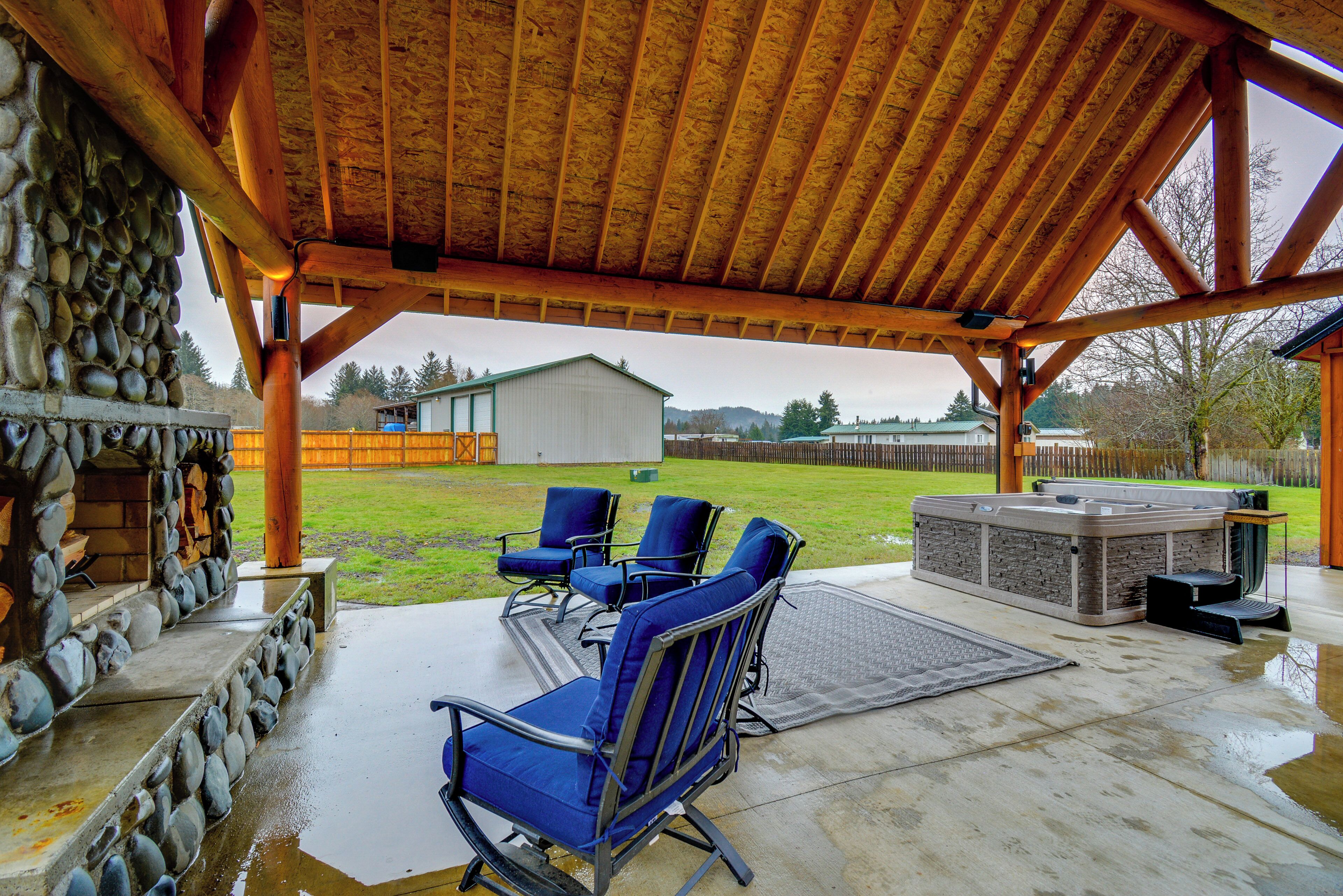 An outdoor patio with stone walls, a hot tub, and blue chairs.