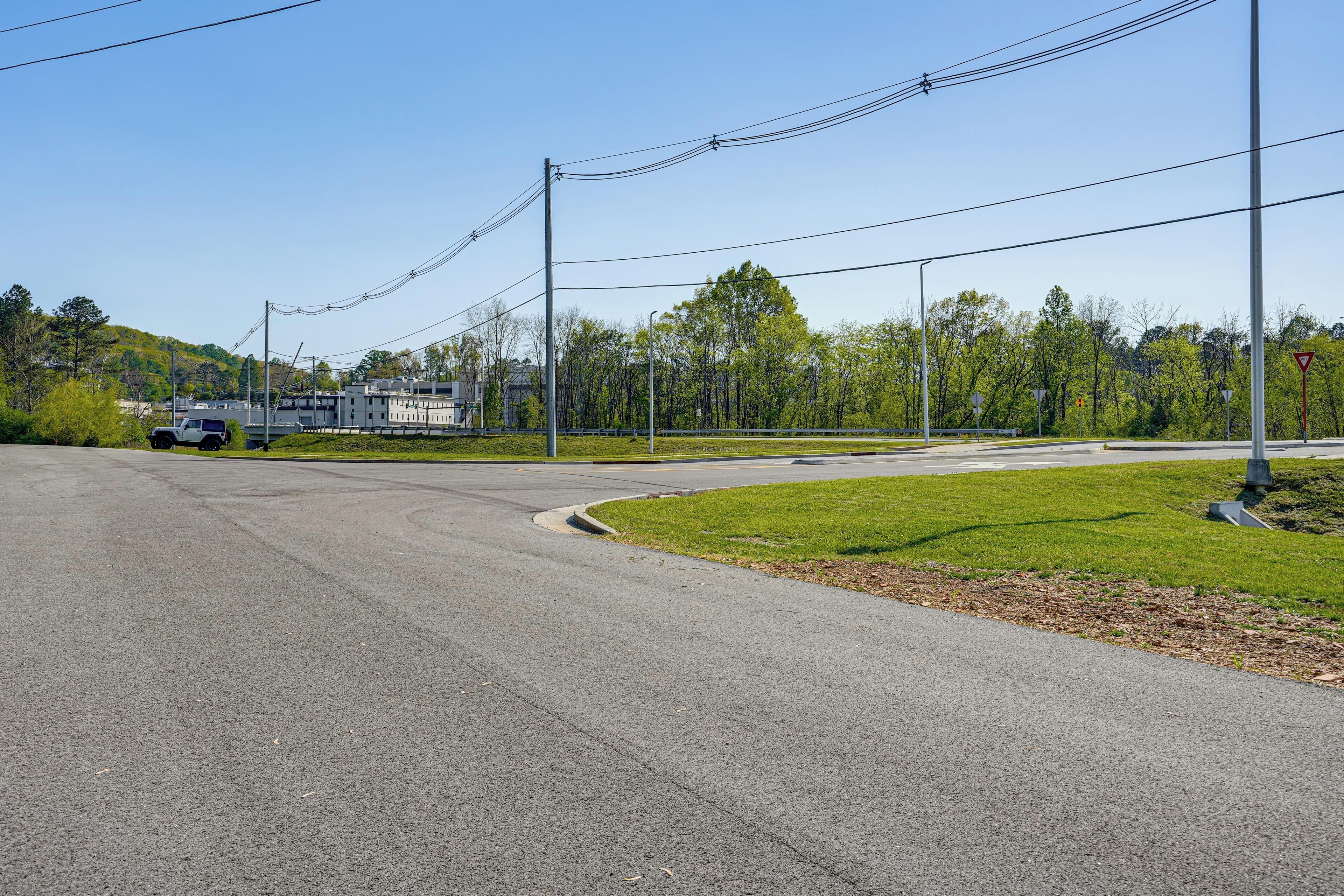 A road with a curve, a grassy area, and a building in the background.