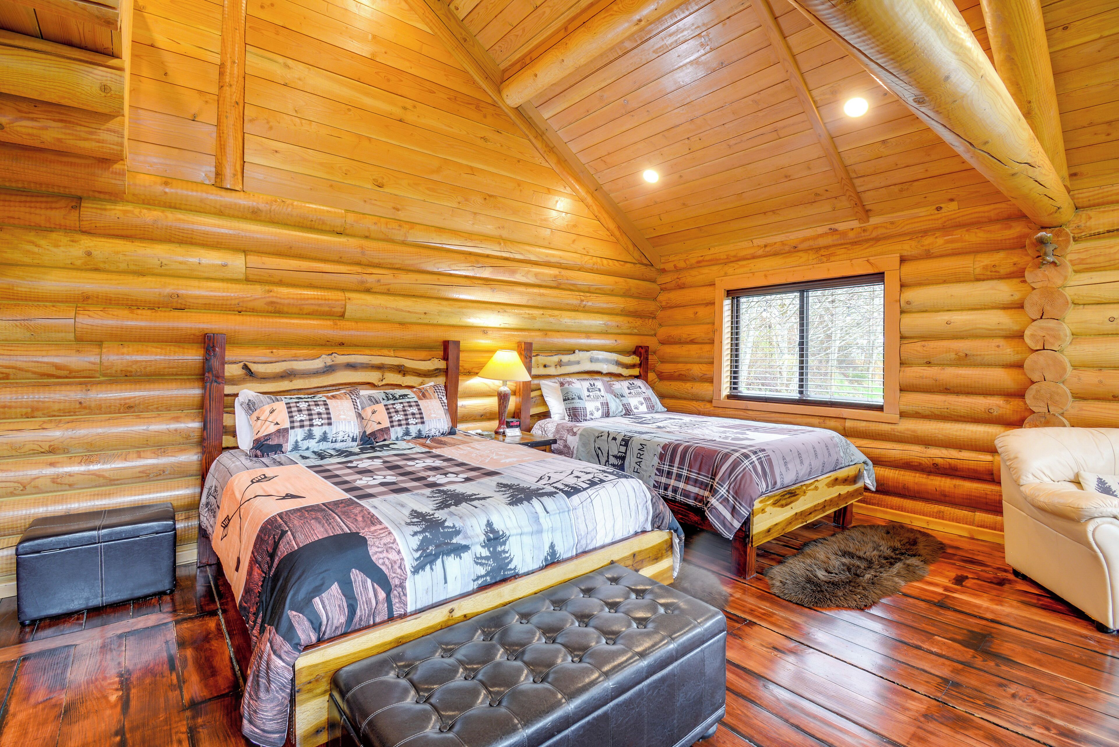 A log cabin bedroom with two beds, a sofa, and a window.