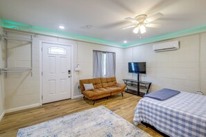Ein Zimmer mit einem Bett, einer Couch, einem Fernseher und einem Deckenventilator.