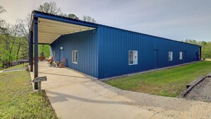Un grand bâtiment industriel bleu, doté d’un espace extérieur abrité, d’un chemin en béton et d’une pelouse.