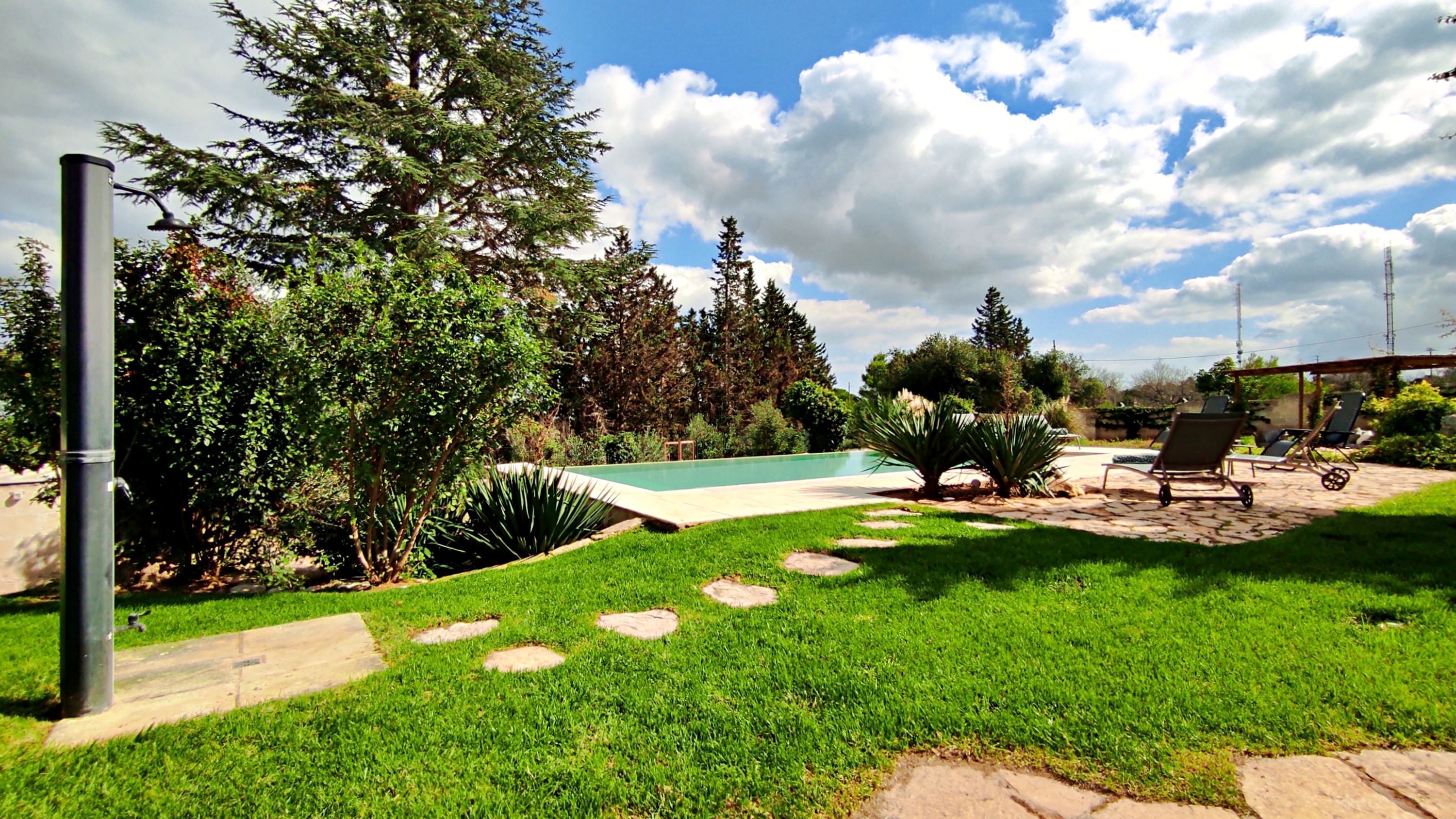 A backyard with a swimming pool, stone steps, and outdoor furniture.