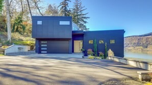 A modern two-story house with a garage, a driveway, and a lake view.
