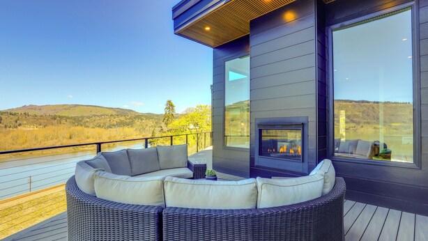 A modern outdoor seating area with a built-in fireplace, overlooking a scenic landscape.