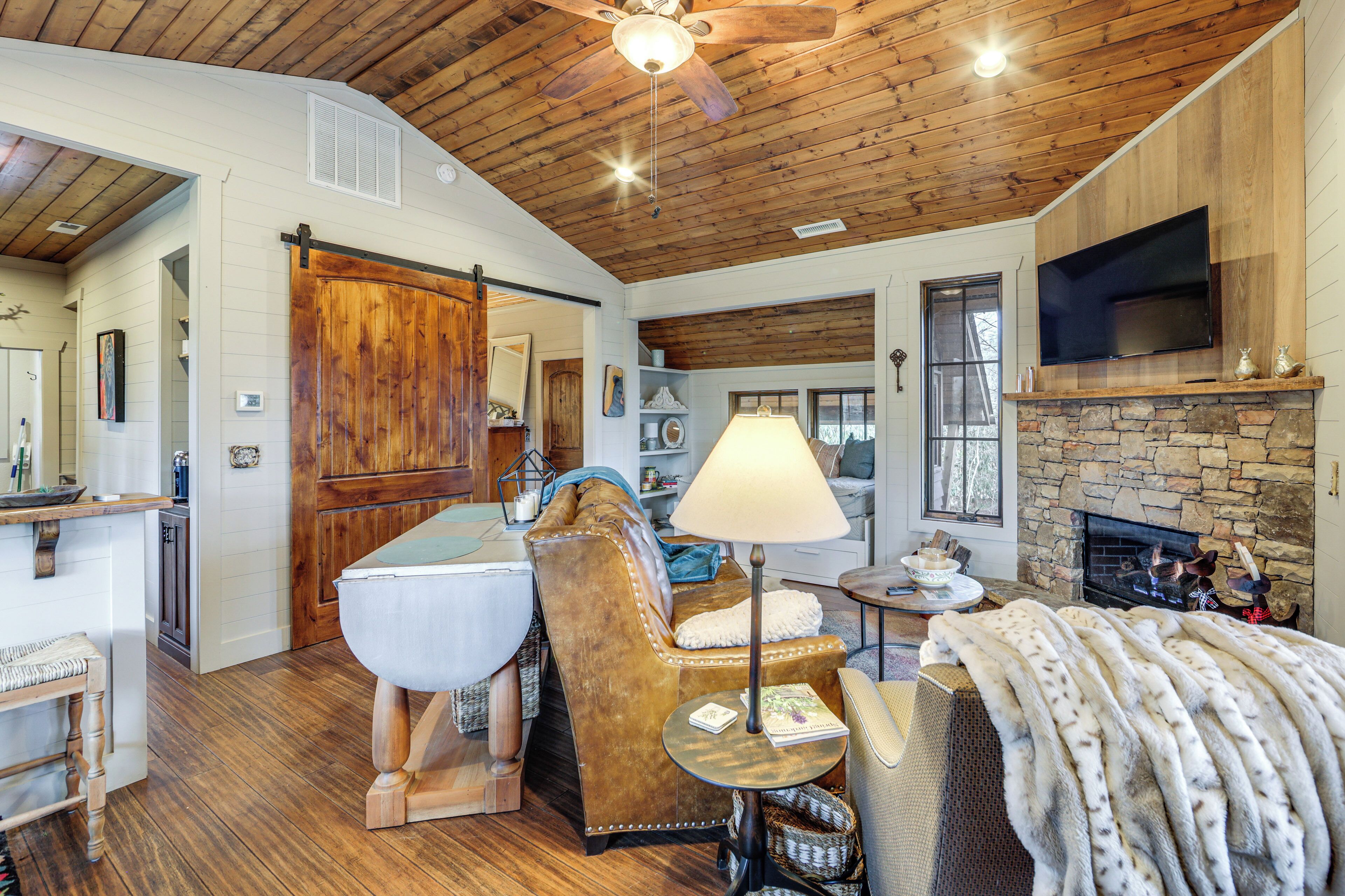 A cozy living room with a fireplace, wooden ceiling, and a television mounted above it.
