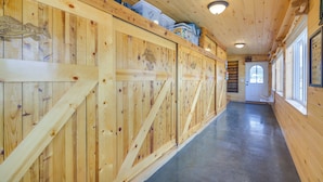 Un couloir en bois avec un plancher ciré, une porte au fond et des récipients en plastique accrochés au mur.