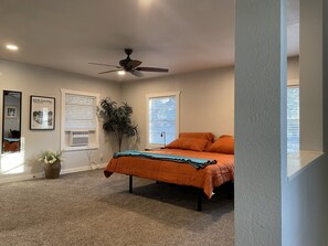 Una camera da letto con un letto, un ventilatore a soffitto, finestre e una pianta.
